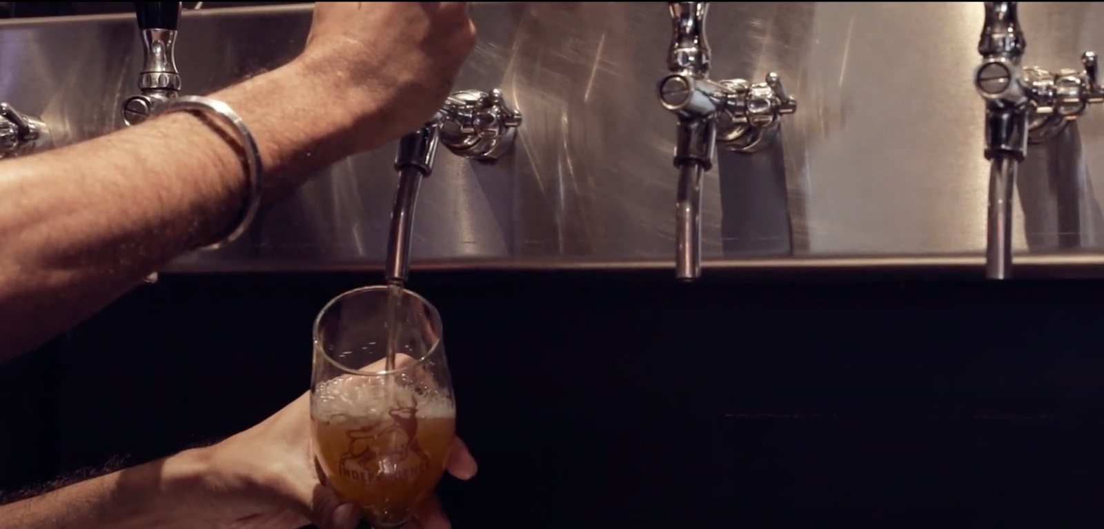 A bartender pours a craft beer from the taps