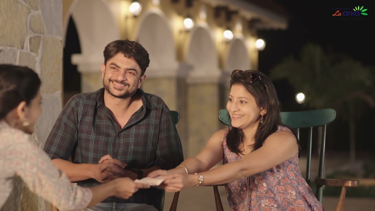 Still from the La Arka ad film: friends laughing on an arched patio at dusk
