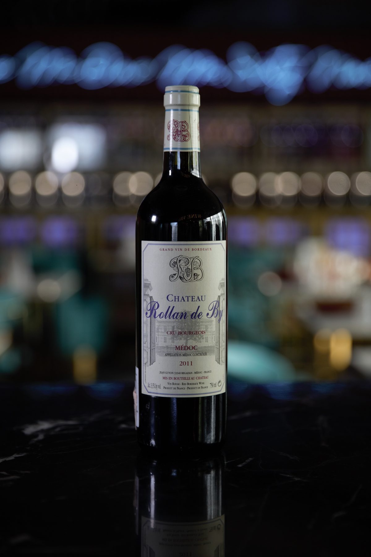 Bottle of Château Rollan de By on a bar counter at night